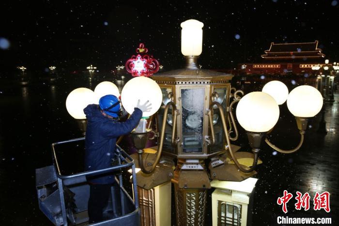 图为国网北京电力城市照明管理中心华灯班成员雪天巡修广场内的华灯设备。　魏晓彬 　摄