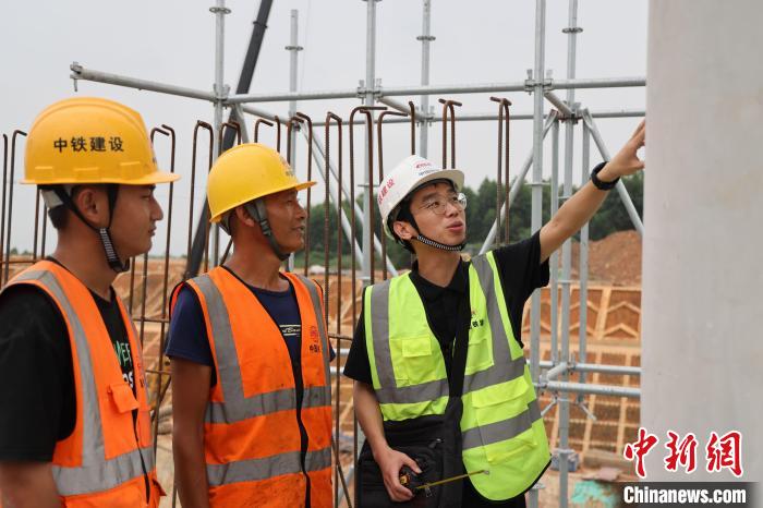 图为杨明伟(右一)在指导工作人员进行对清水混凝土的养护工作。　资音 摄