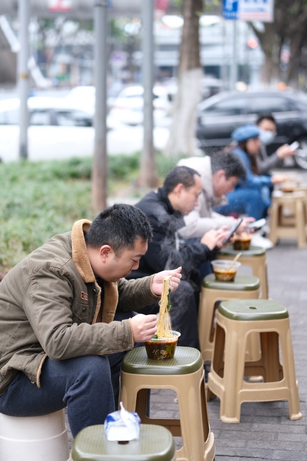 12月2日，南岸区铜元局长江村，街头一小面馆，市民在路旁吃面。郭旭摄
