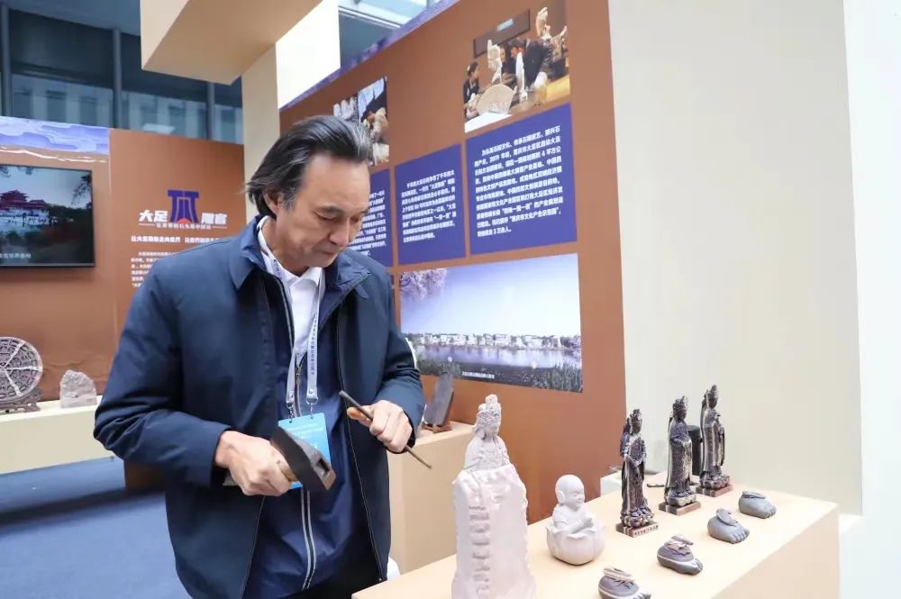 “大足雕客”形象代言人刘能风在参展现场展示精湛的大足石雕技艺。市人力社保局供图