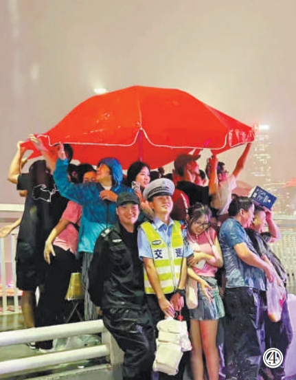 重庆市公安局江北区分局交巡警支队辅警夏英柯在执勤中偶遇暴雨，与市民、游客一同避雨。重庆市公安局江北区分局供图
